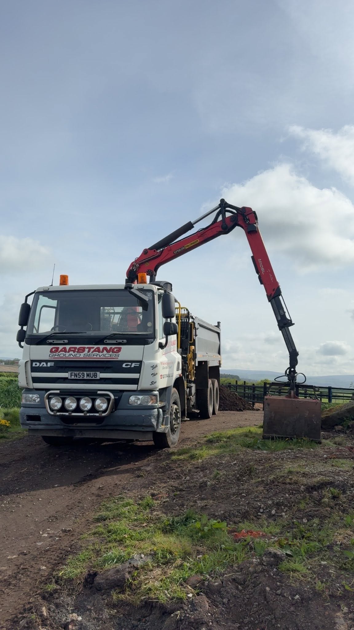 Grab lorry collecting construction soil from a field