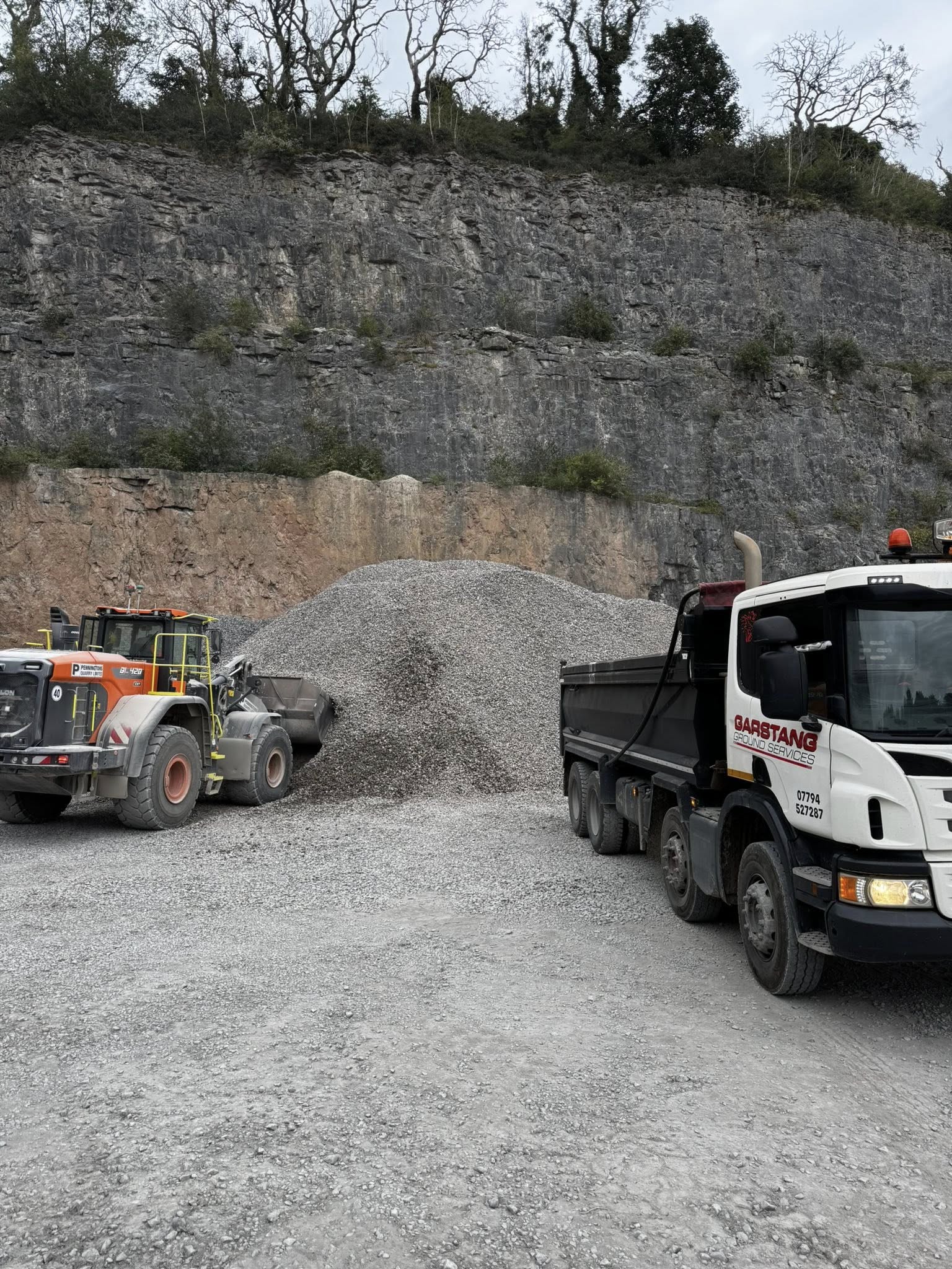 Grab lorry loading inert waste during construction site clearance